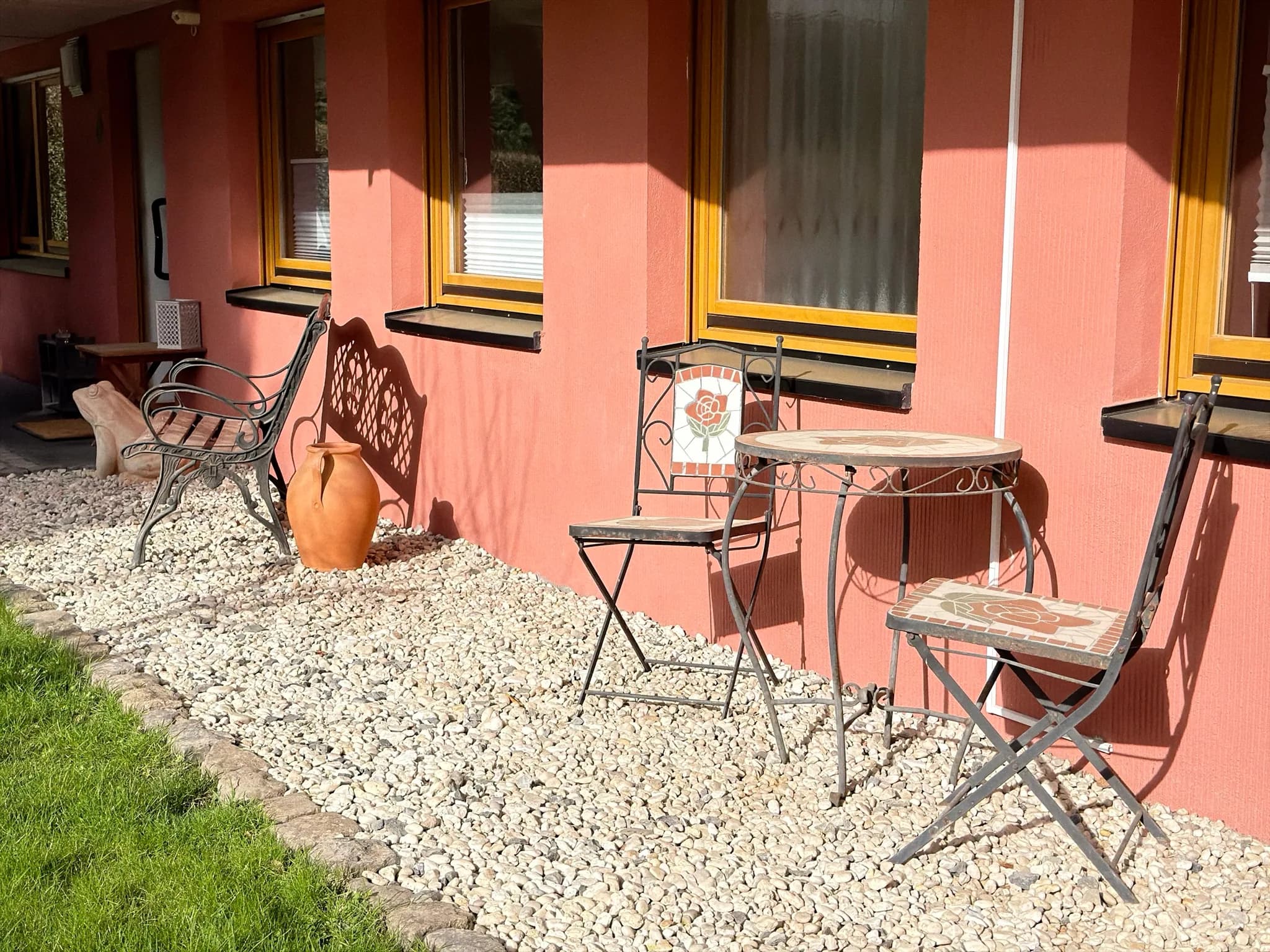 Terrasse mit Bistro-Set, Gartenbank und Blick auf den Rasen.